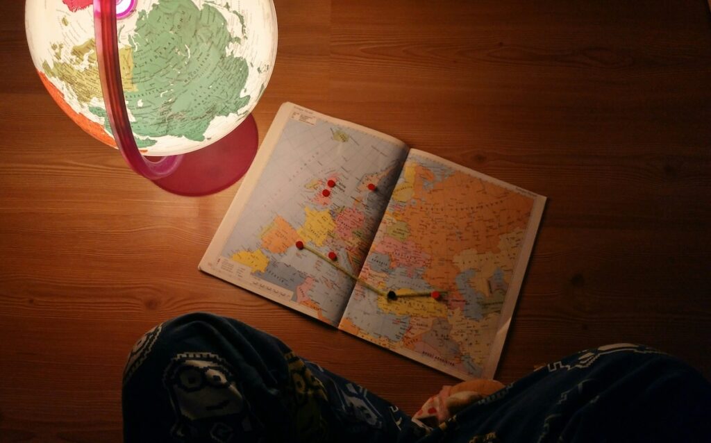 map with pins in it on desk next to globe