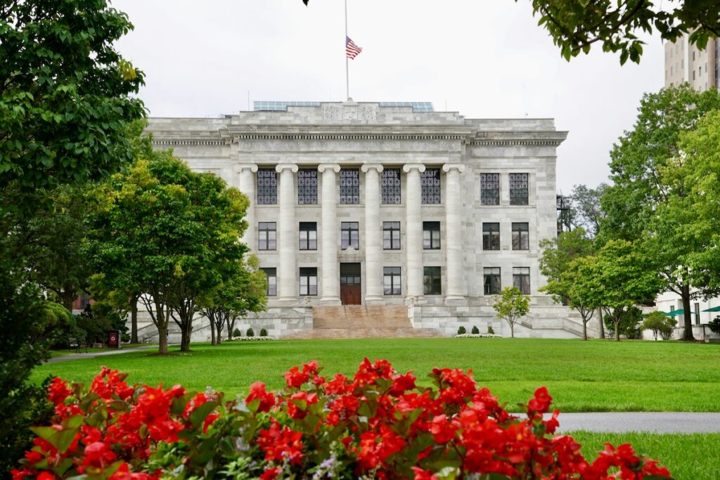 exterior of Harvard University building with red flowers in foreground