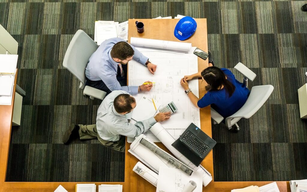 three professionals work collaboratively around a desk in an office