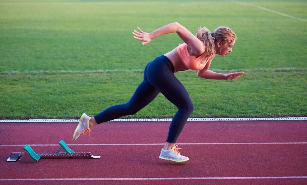 woman sprinter leaving starting blocks on the athletic track.