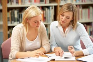 A parent and high school student reviewing college application materials together.