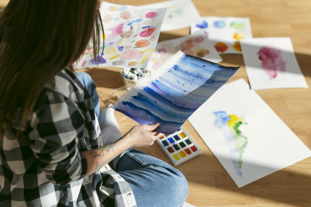 student sorts through pieces of artwork