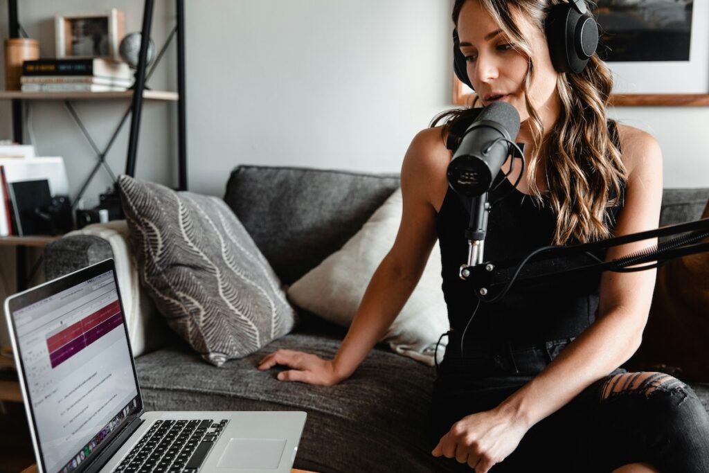 student records a podcast using a podcast mic and laptop in her living room