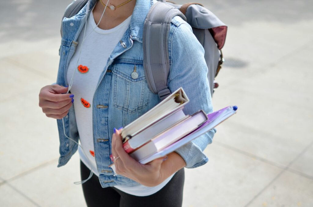 student carrying an armful of text books