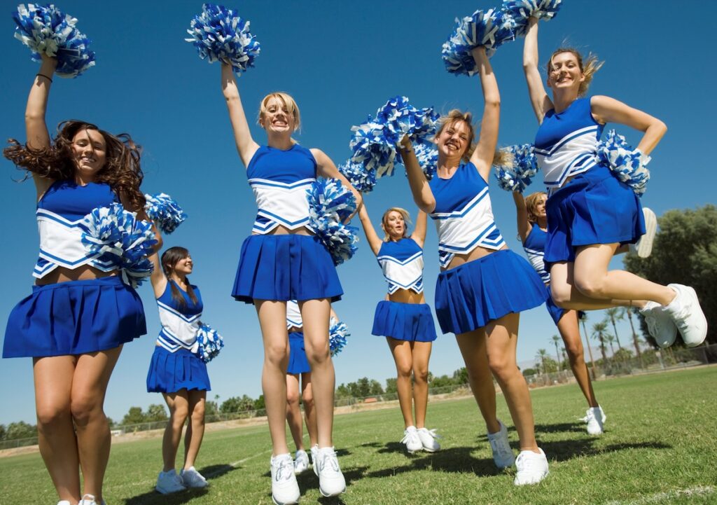 cheerleaders in blue and white uniforms jump off the ground