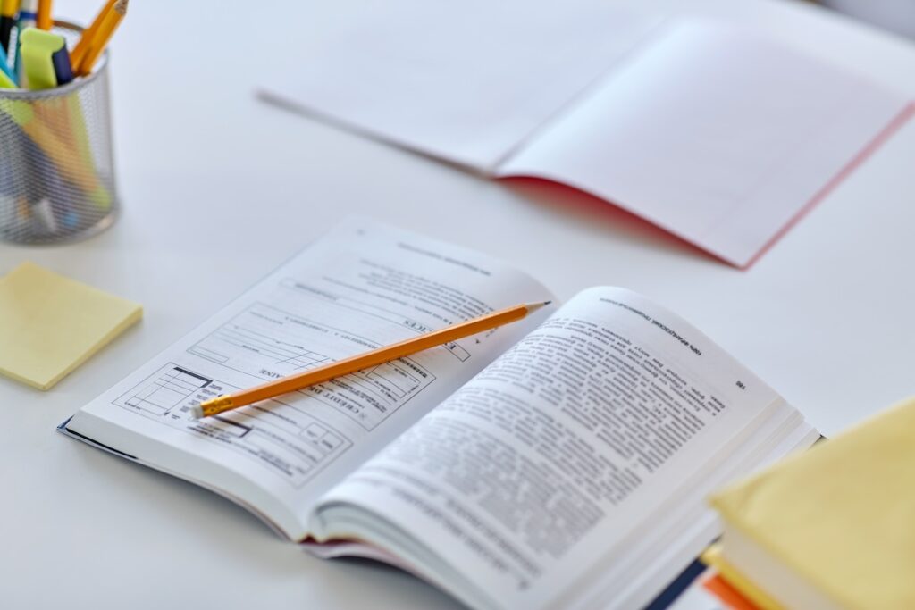 close up of book, pencil, notebook and school supplies on table