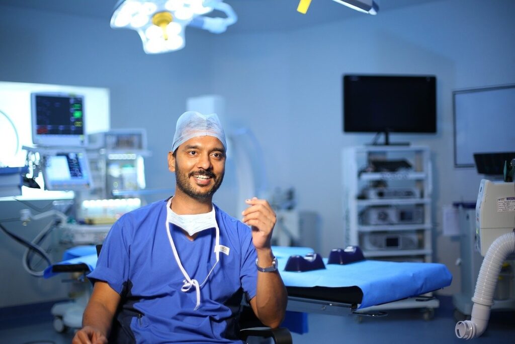 surgeon in operating room smiles at the camera