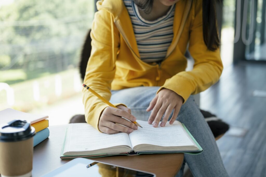 girl in yellow sweatshirt studies textbook