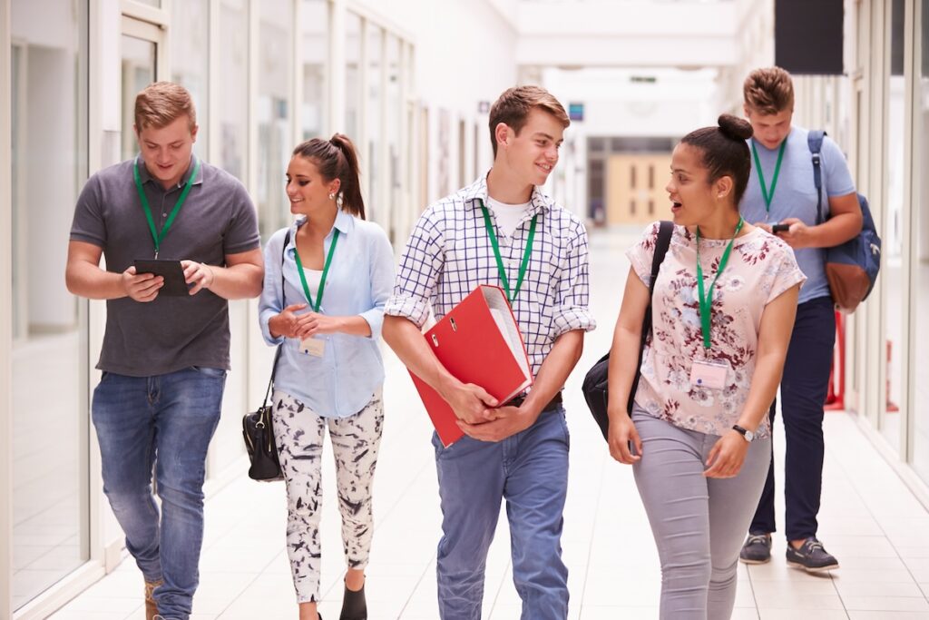 Group Of Students Walking Along Corridor