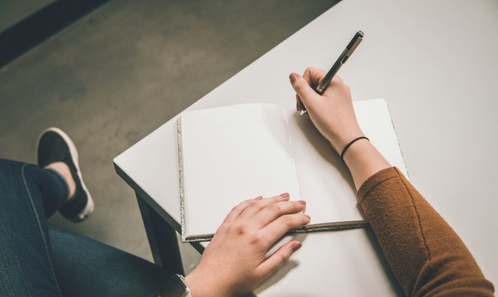 close up of person's hand writing in notebook