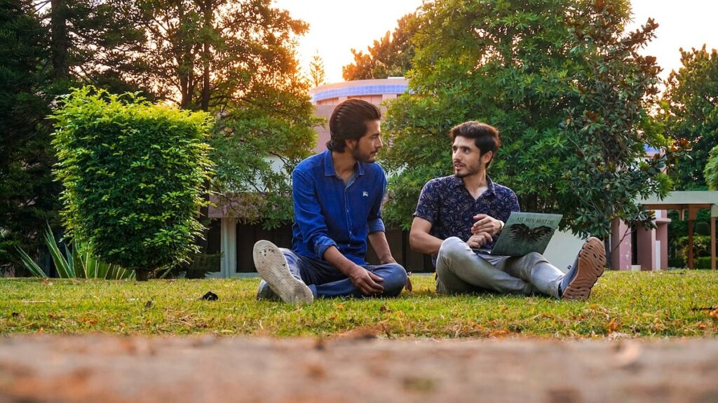 two friends sit outside on a college campus
