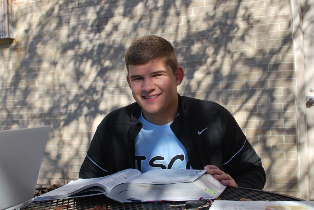 student reviews thick textbook on a table outdoors