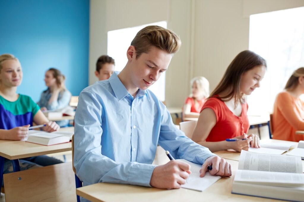 group of students with books writing school test