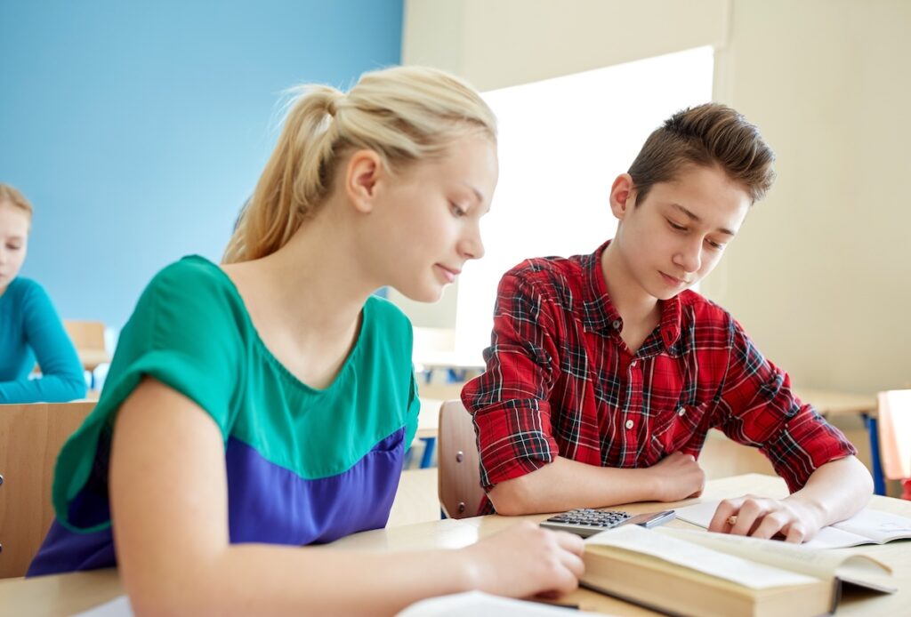 students with book and calculator at school lesson
