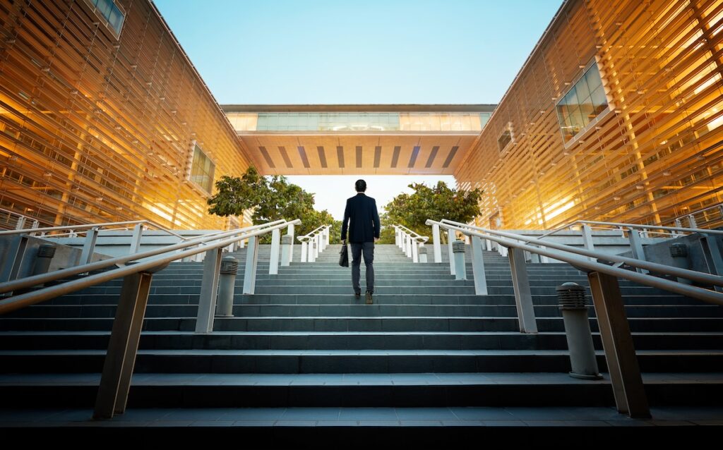 business student walking up steps at modern building