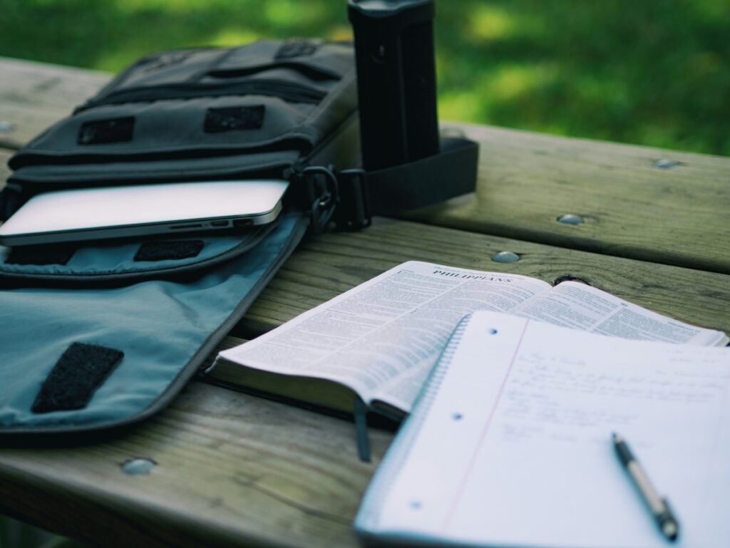 study notes and laptop in backpack on top of picnic table