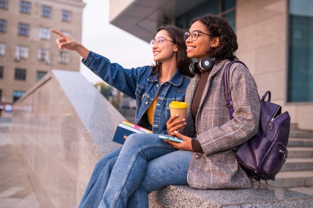 two female students analyze something out of frame on a university campus