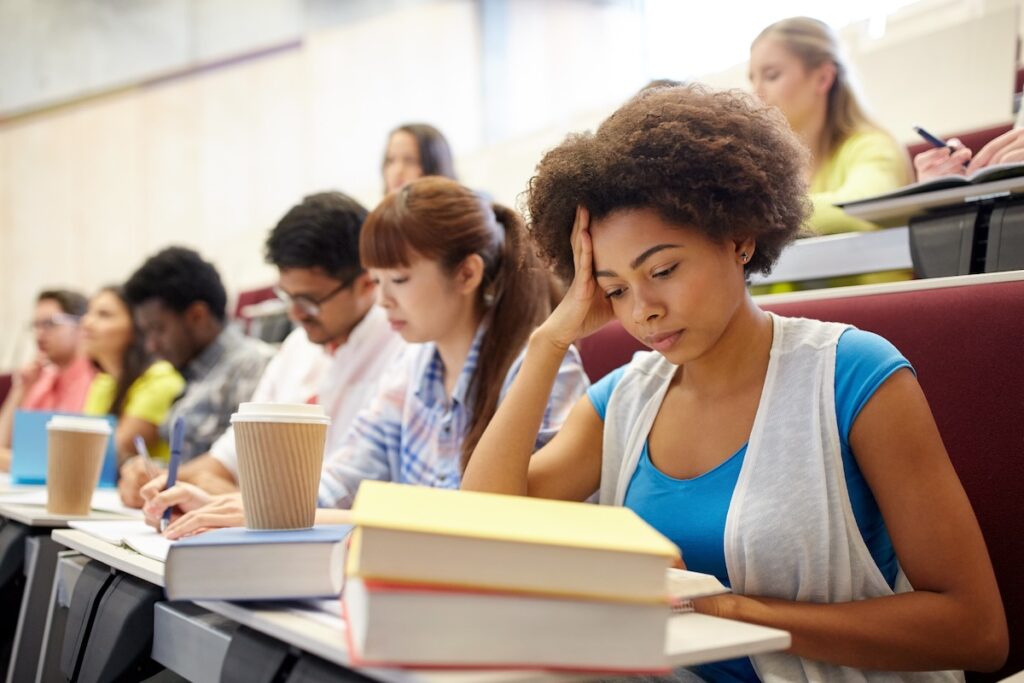group of international students with notebooks and coffee writing test in lecture hall