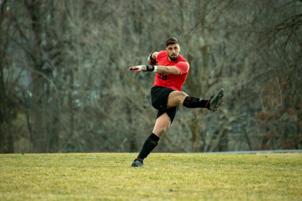 male athlete kicking a ball on a field