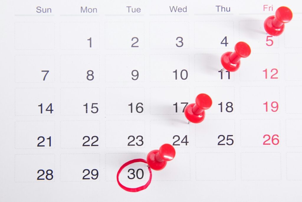 calendar with red pins on some of the dates indicating deadlines