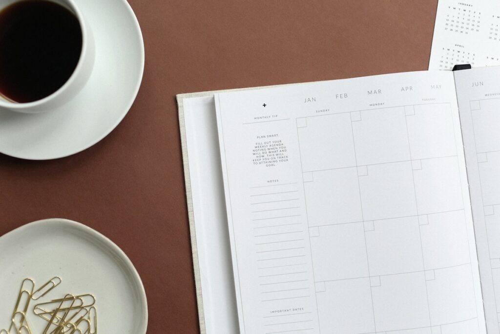 calendar page open on table next to cup of coffee