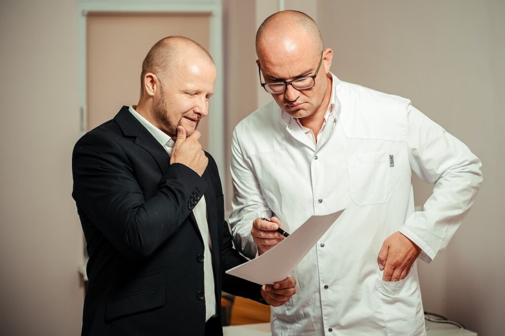 a doctor consults with a man in a suit in an office