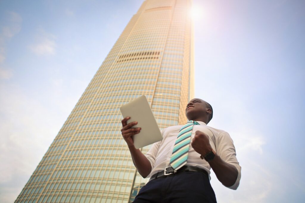 man holds tablet in front of tall building