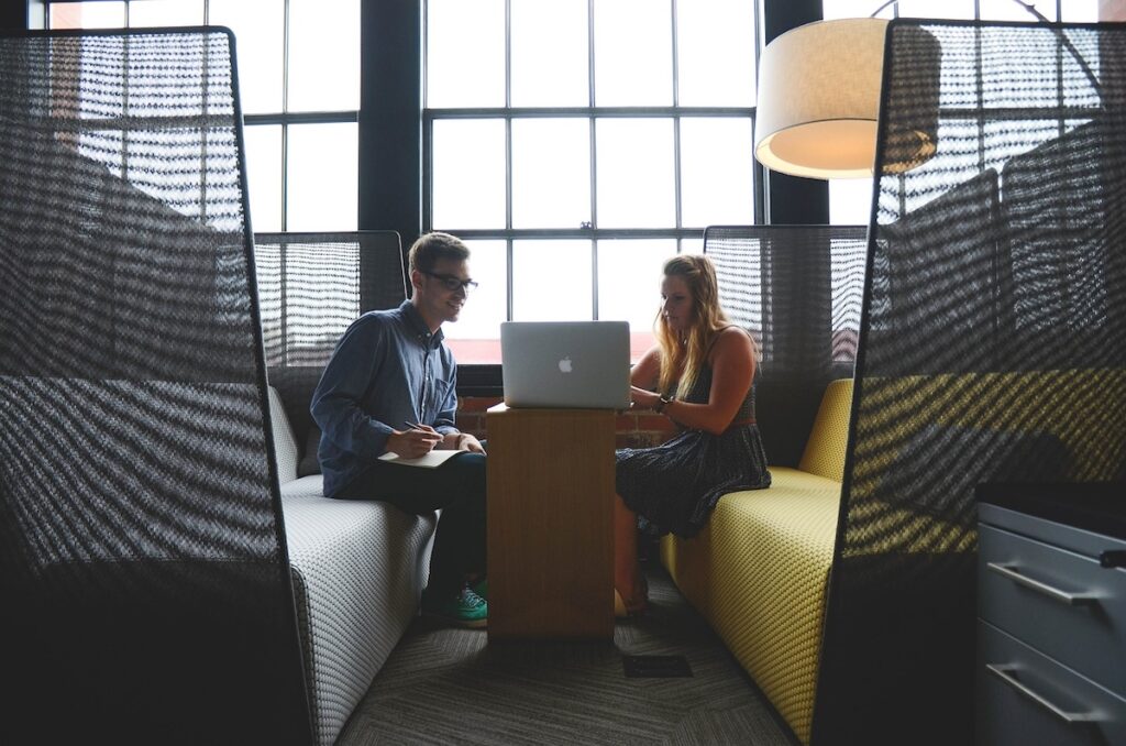 two employees huddle around a laptop in a startup office