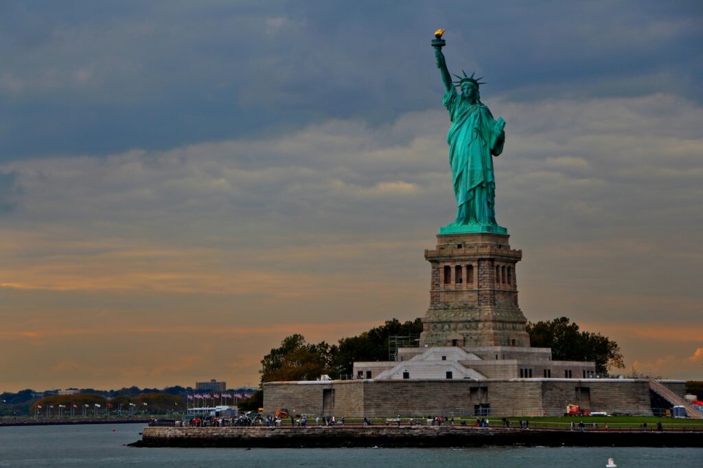 statue of liberty from afar with the sunset in the background