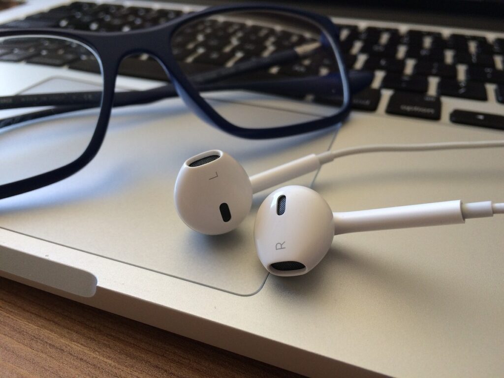 laptop with a pair of glasses and airpods resting on it