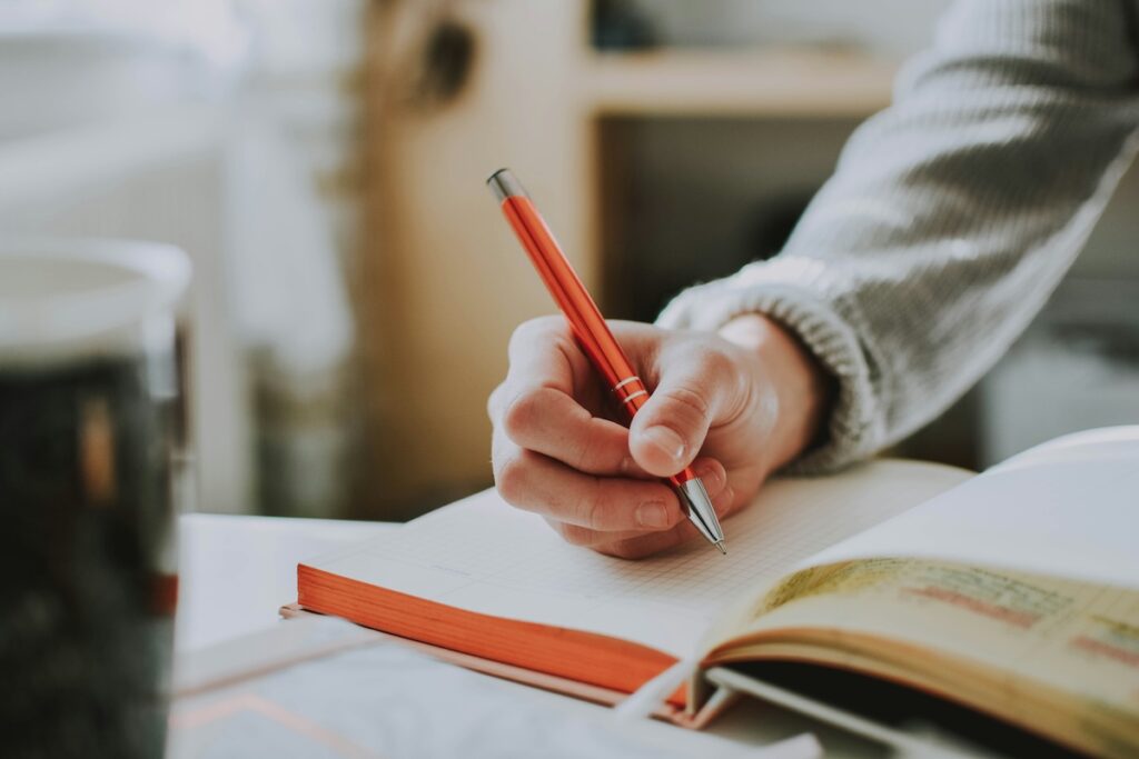 writing in notebook with orange pen