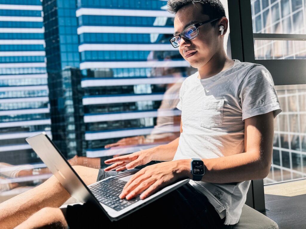 student working on laptop in front of window