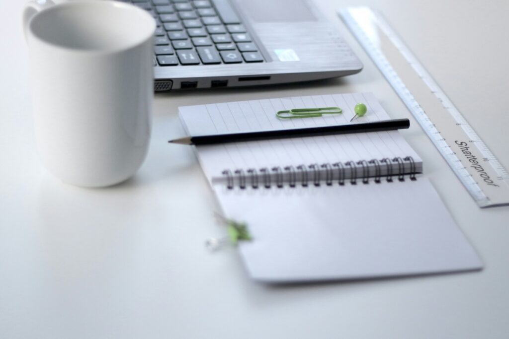 laptop with notebook and cup of coffee next to it