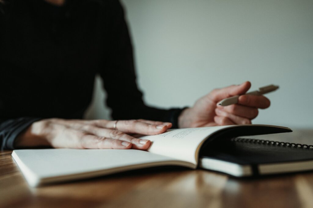 person writing in notebook on a wooden desk