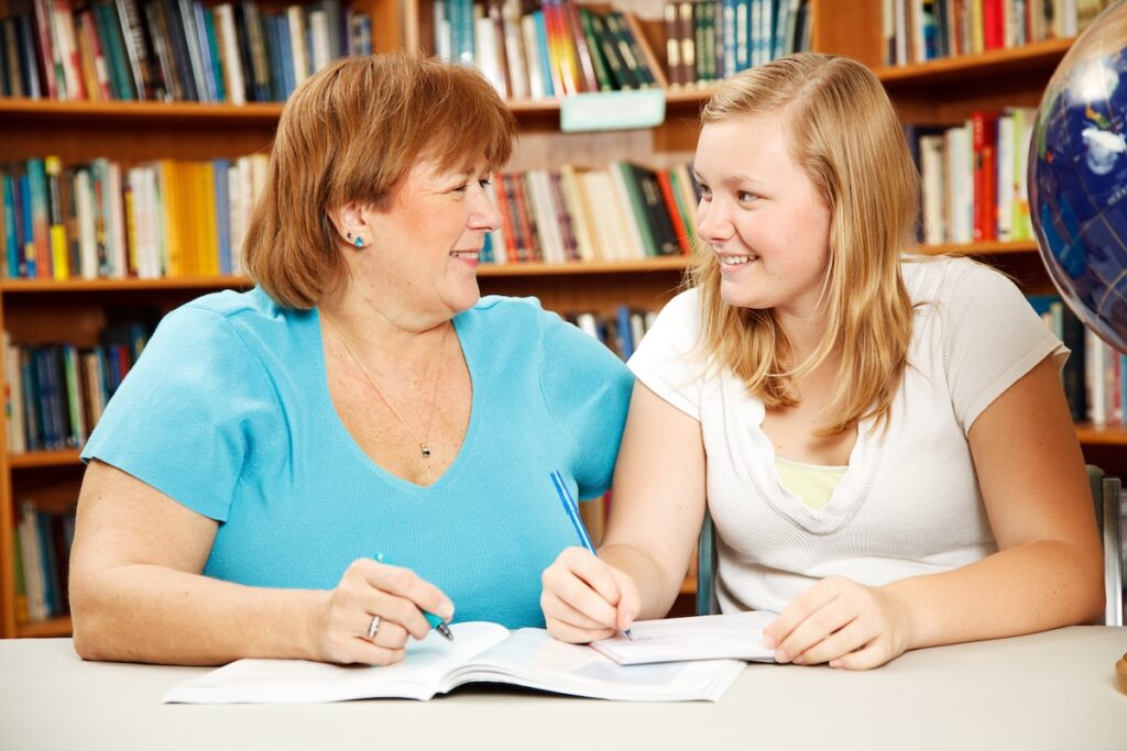 Mother helping a teenage girl study in the school library.