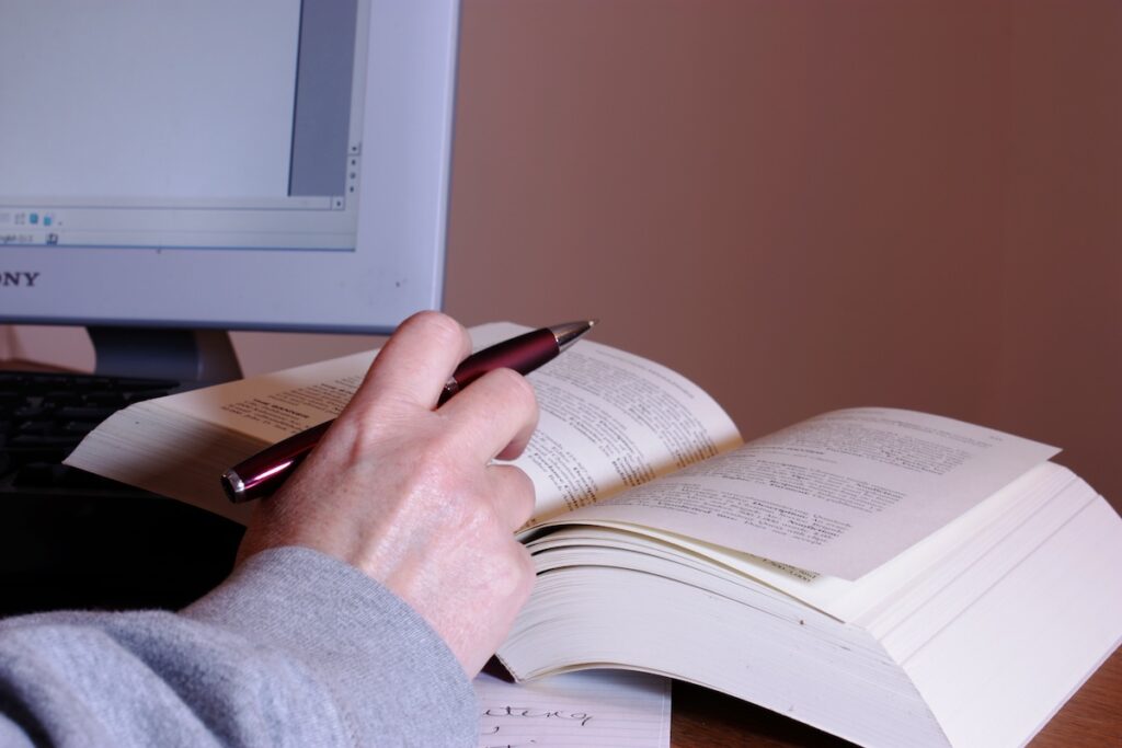 student takes notes while reading a book