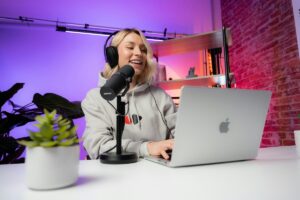 woman at a laptop speaks into a microphone on a video set