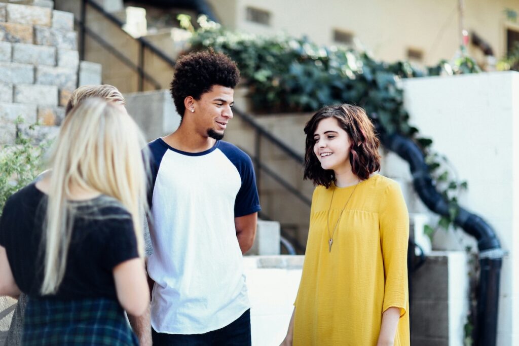 three high school students stand together chatting