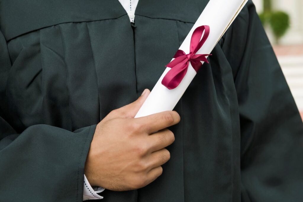 graduate holds diploma against their chest