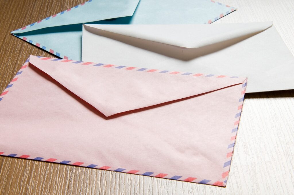 three envelopes, one blue, one white and one pink