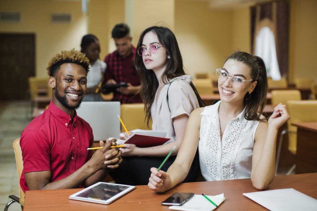 college students smile while working on papers at a table