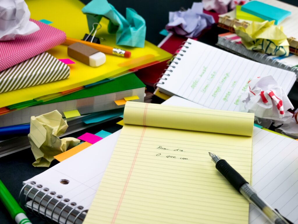 notepade with writing on it on a desk surrounded by study materials