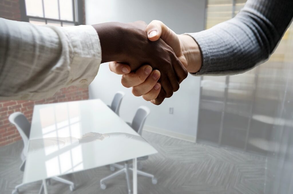 two people shake hands in front of modern looking office space