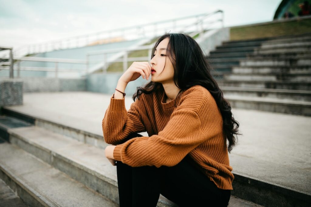 woman sits on outdoor steps thinking