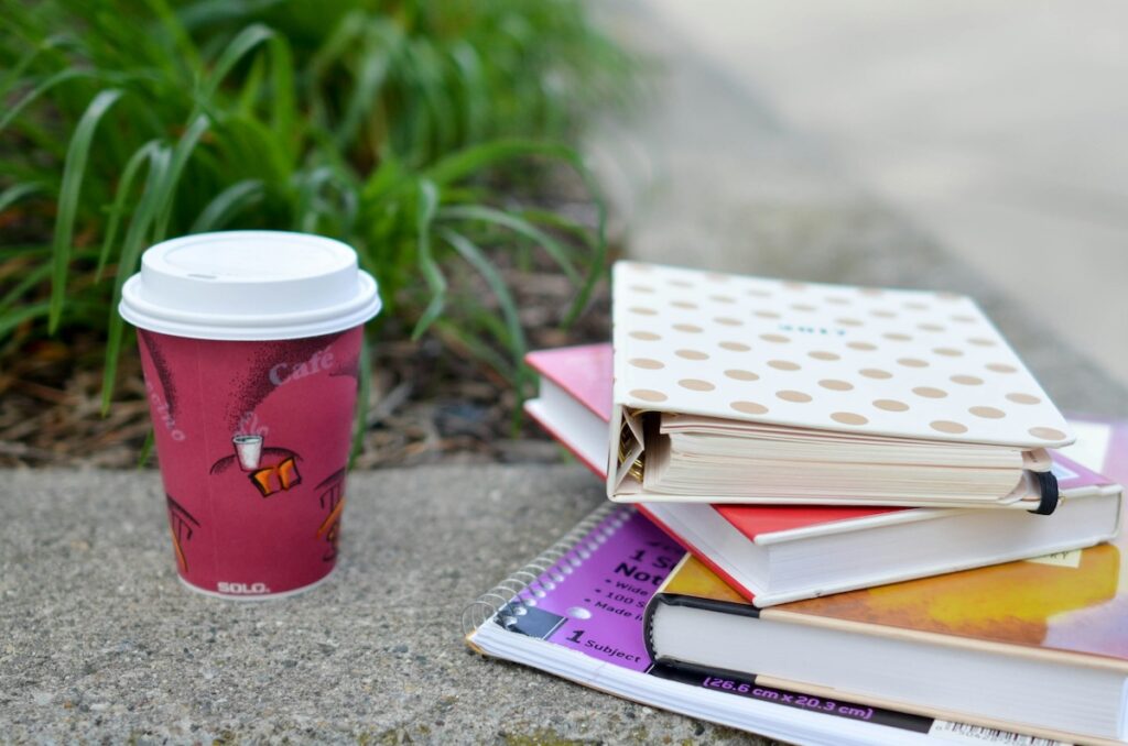 pile of study materials next to a cup of coffee