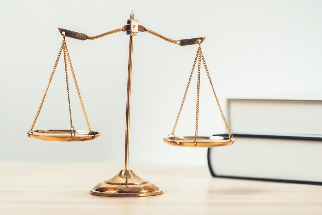 Shiny golden balanced scale and law book on desk in law school as concept justice and legal symbol. Scale balance for righteous and equality judgment by lawyer and attorney. equility