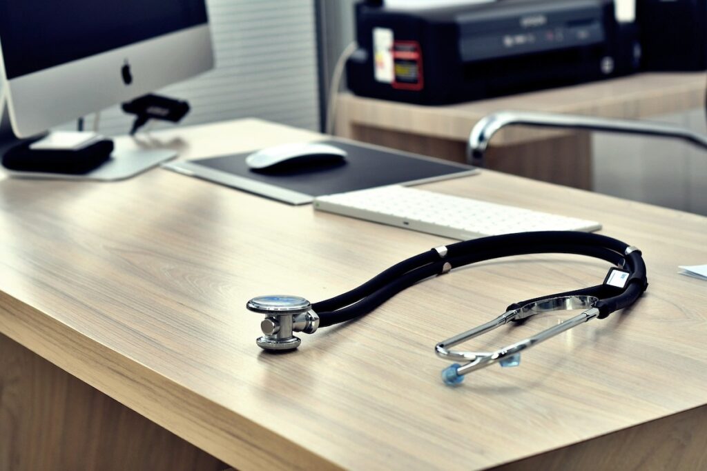 stethoscope sits on modern desk with iMac