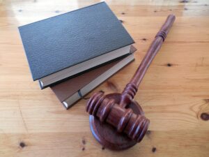 judge's gavel sits on wooden desk next to two books