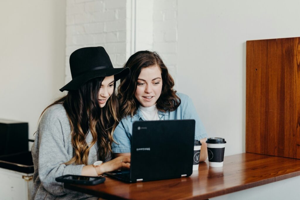 two students looking at laptop in a coffee shop
