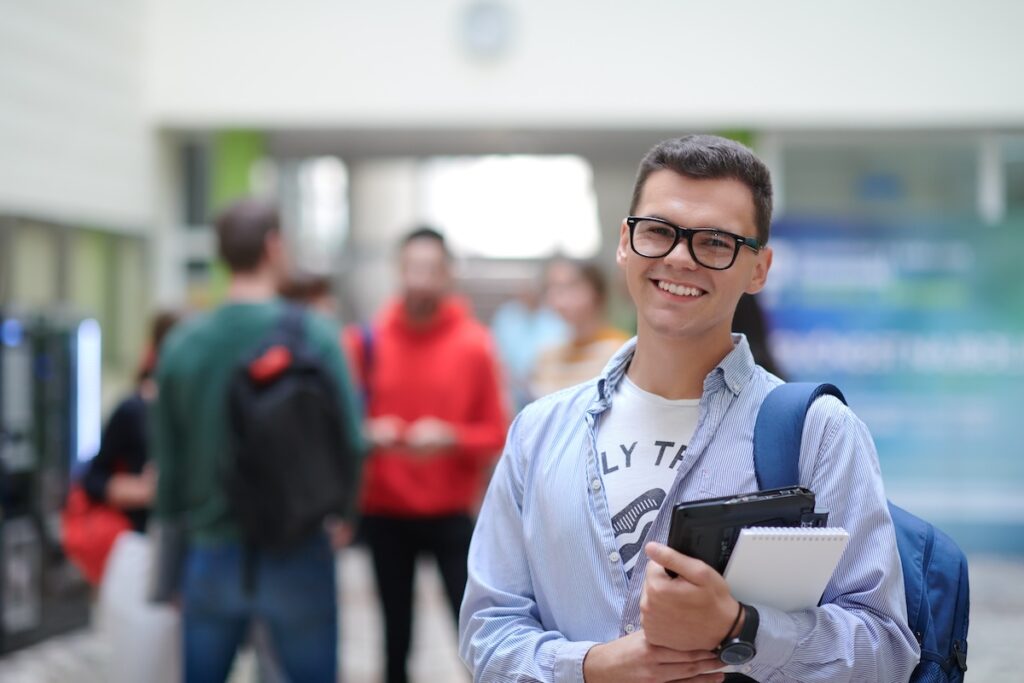 a student in glasses stands in the hallway of a modern school